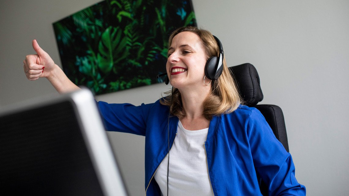 Mit Herz und Expertise bei der Arbeit. mindshape-Agenturleben: Mitarbeiter:in hält Daumen nach oben, während sie per Headset telefoniert.