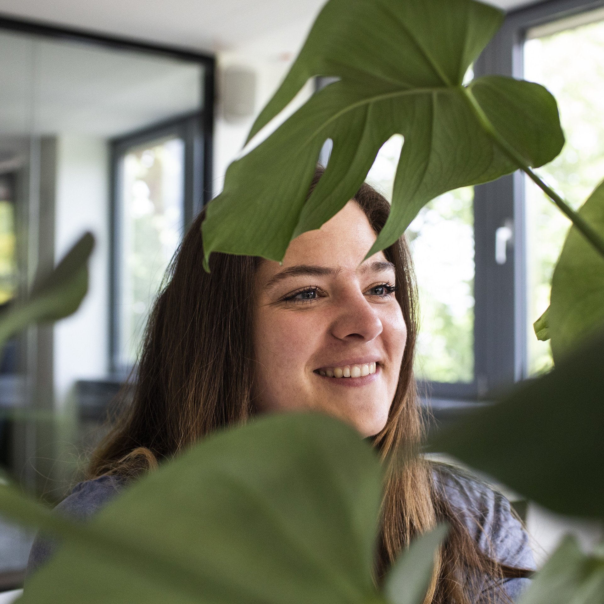 Ein gesundes Arbeits- und Raumklima gehört zur mindshape-Kultur. mindshape-Benefits: Eine Person posiert mit Pflanzen.
