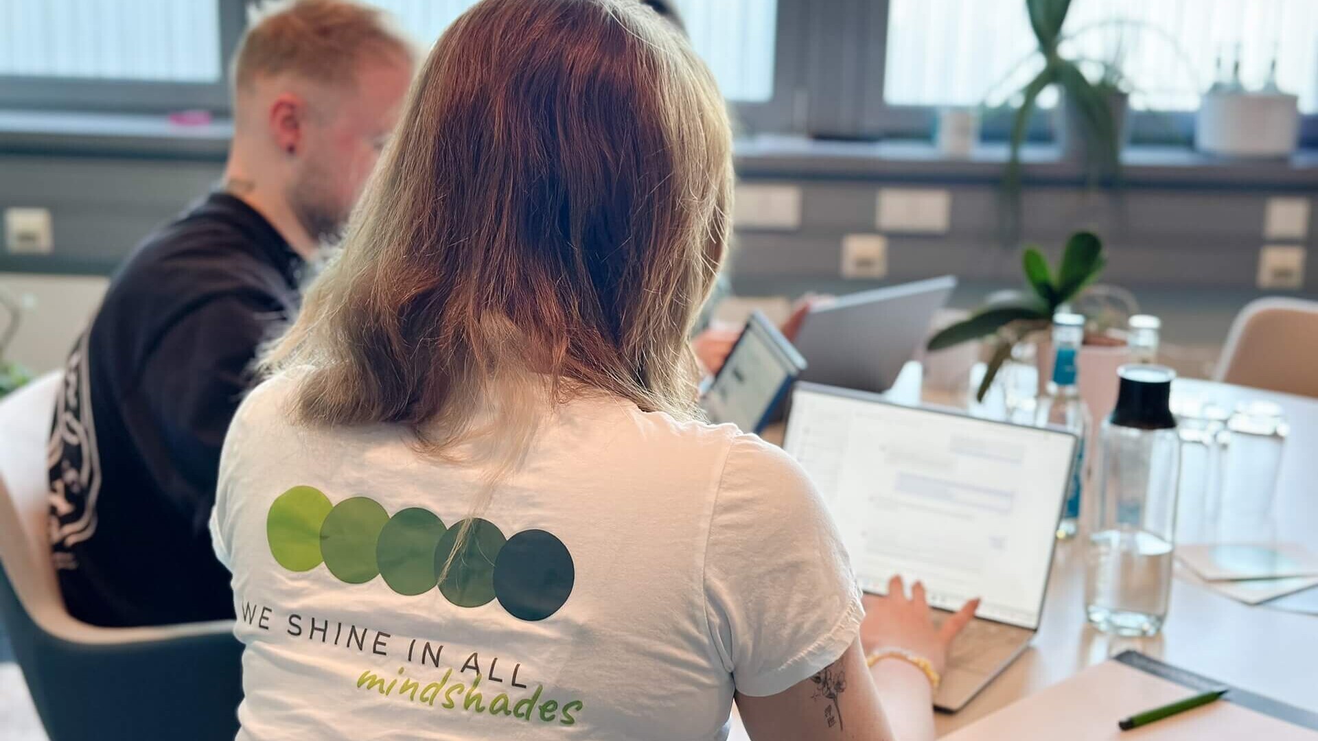 Mitarbeiterin von mindshape sitzt mit Laptop am Tisch