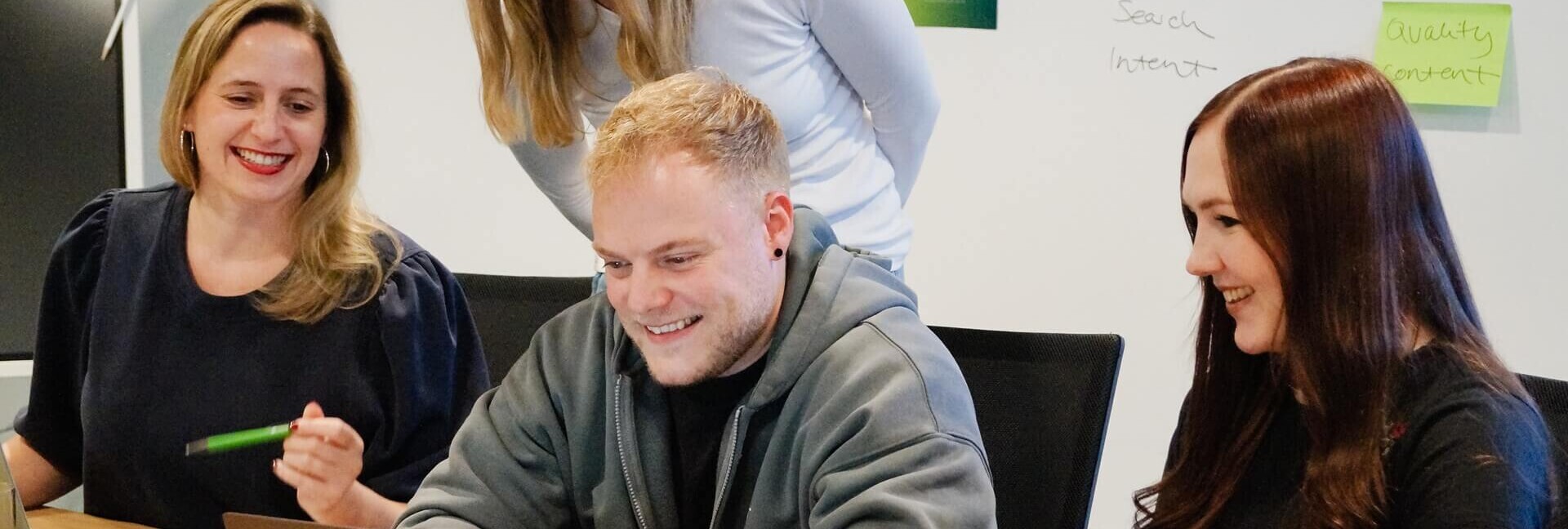 Meeting eines Onlinemarketing-Teams bei mindshape Vier Personen sitzen vor einem Laptop am Tisch im Konferenzraum