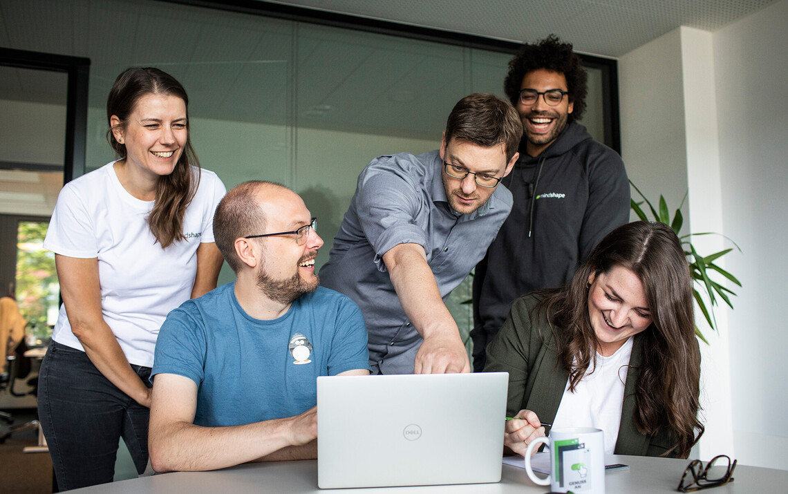 Online Marketing Agentur: Mitarbeiter:nnen schauen gemeinsam auf Laptop